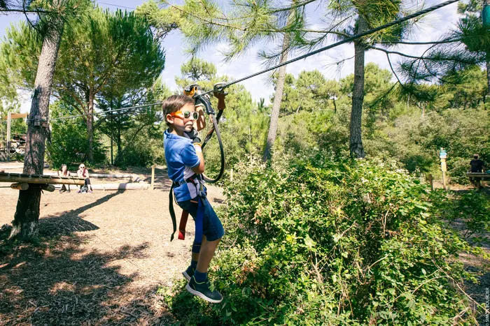 Enfant effectuant une activité d'accrobrnche dans une foret ensoleillé de Loire Atlantique